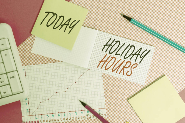 Writing note showing Holiday Hours. Business photo showcasing employee receives twice their normal pay for all hours Writing equipments and computer stuffs placed above colored plain table. - Photo, Image