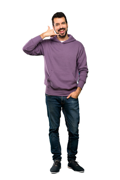 Full-length shot of Handsome man with sweatshirt making phone gesture. Call me back sign over isolated white background - Foto, Imagem