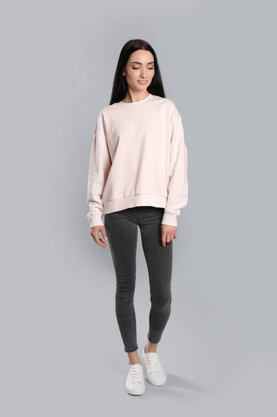 Full length portrait of young woman in sweater on grey background. Mock up for design - Zdjęcie, obraz