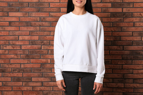 Young woman in sweater at brick wall, closeup. Mock up for design - Foto, Imagem