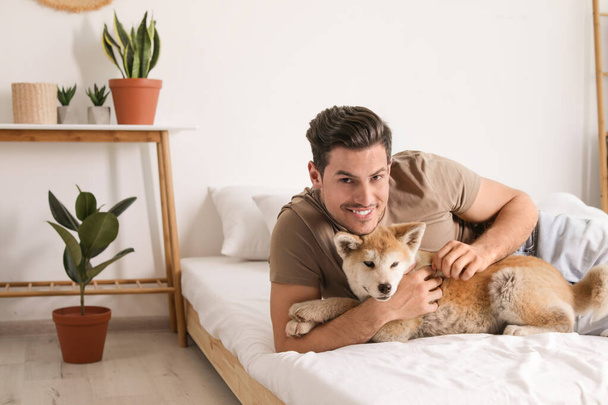 Man and Akita Inu dog in bedroom decorated with houseplants - Foto, Imagem