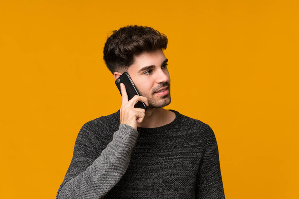 Fiatal férfi elszigetelt háttér miközben egy beszélgetést a mobiltelefon valakivel - Fotó, kép