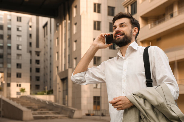 Handsome man talking on phone in modern city - Foto, imagen
