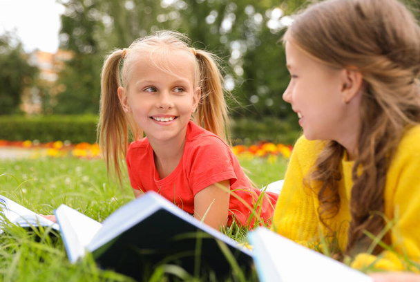 Meninas bonitos lendo livros na grama verde no parque
 - Foto, Imagem