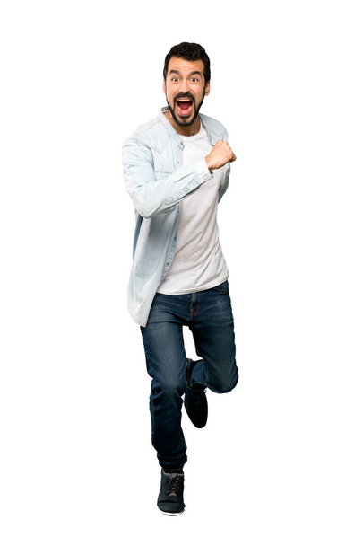 Full-length shot of Handsome man with beard running fast over isolated white background - Фото, зображення