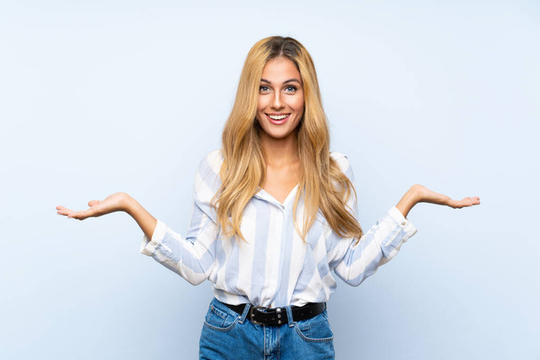 Young blonde woman over isolated blue background with shocked facial expression - Photo, Image