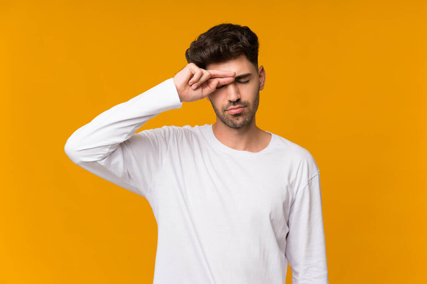 Young man over isolated orange background with tired and sick expression - Fotó, kép