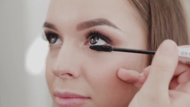 Professionele make-up kunstenaar vrouw schildert wimpers aan cliënt van schoonheid salon. - Video