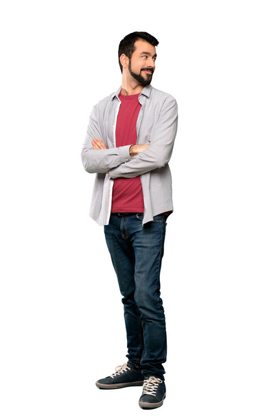 Full-length záběr pohledný muž s plnovousem se zkříženýma rukama a šťastný přes izolované bílé pozadí - Fotografie, Obrázek