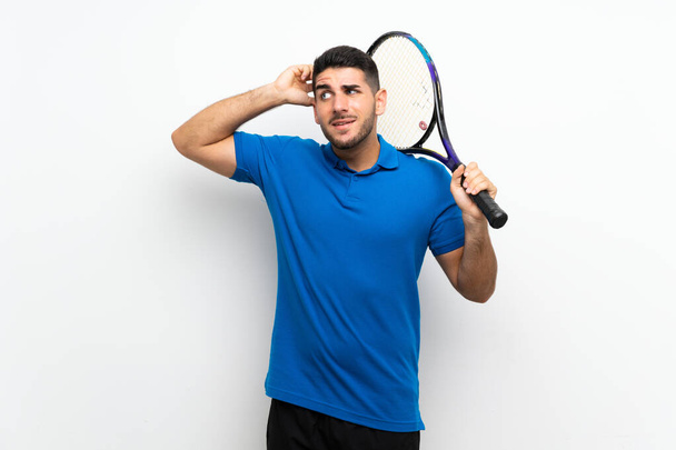 Bonito jovem jogador de tênis homem sobre a parede branca isolada com dúvidas e com expressão facial confusa
 - Foto, Imagem