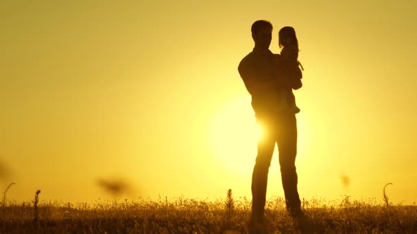 Tata ukochany dziecko w jej ramionach tańczy w locie i śmieje się. Szczęśliwe dziecko bawi się z ojcem o zachodzie słońca. Sylwetka mężczyzny i dziecka. Koncepcja rodziny - Materiał filmowy, wideo