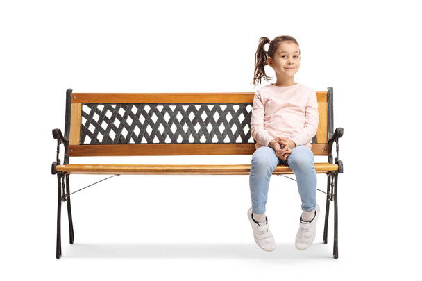 Cute little girl sitting on a bench and looking at the camera  - Foto, Imagem