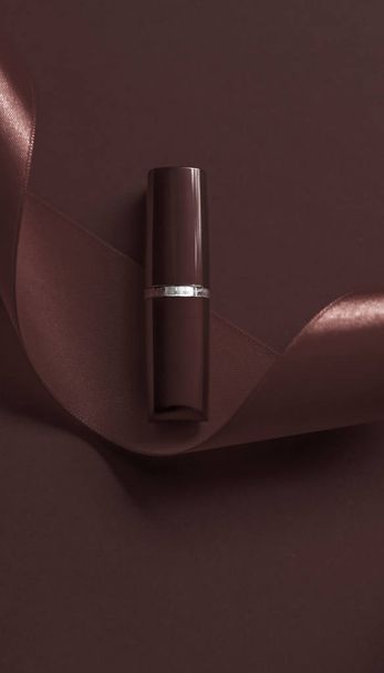 Luxury lipstick and silk ribbon on chocolate holiday background, - Photo, Image