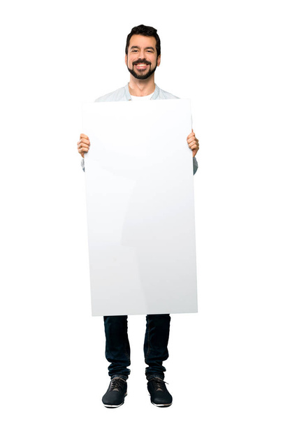 Celovečerní snímek pohledný muž s plnovousem drží prázdný štítek nad izolované bílým pozadím - Fotografie, Obrázek