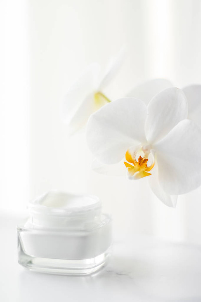 Face cream moisturizer jar and orchid flower, moisturizing skin  - Foto, Imagem