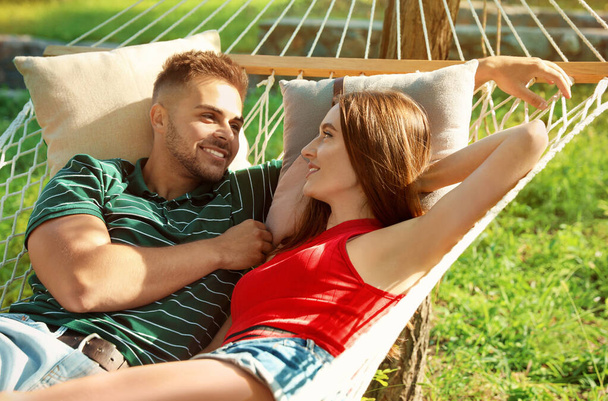 Young couple resting in comfortable hammock at green garden - Foto, Imagen