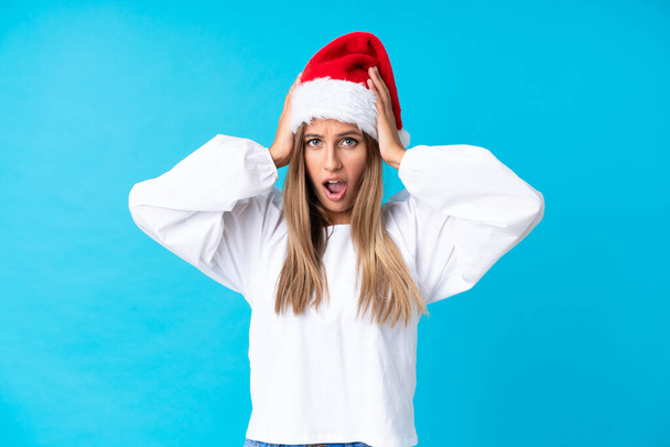 Девушка в рождественской шляпе на изолированном фоне с неожиданным выражением лица - Фото, изображение
