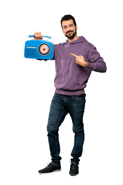 Full-length shot of Handsome man with sweatshirt holding a radio over isolated white background - Foto, Imagem