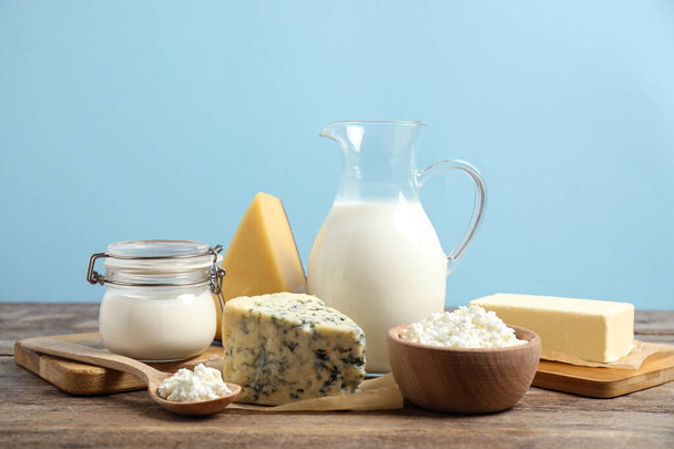 Different dairy products on wooden table against blue background - Φωτογραφία, εικόνα