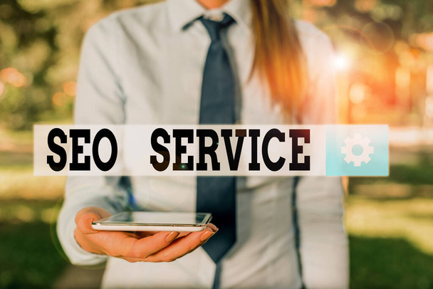 Conceptual hand writing showing Seo Service. Business photo showcasing techniques and procedures to increase the website visibility Business woman in shirt holding laptop and mobile phone. - Photo, image