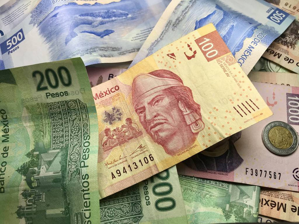 Mexické pesos a další latinskoamerické peněžní poukázky se rozprostřily na dřevěném stole uvnitř malé obchodní kanceláře - Fotografie, Obrázek