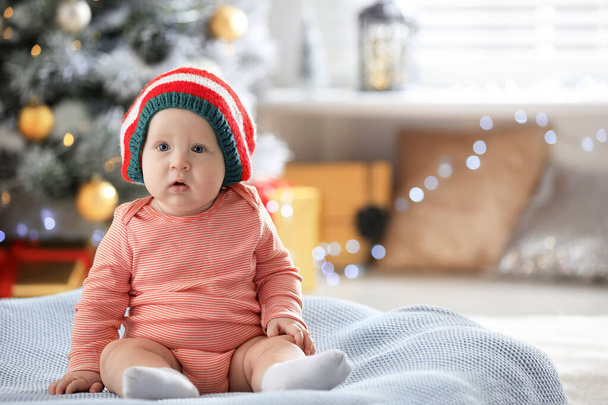 Little baby wearing elf hat on blanket indoors. First Christmas - Foto, afbeelding