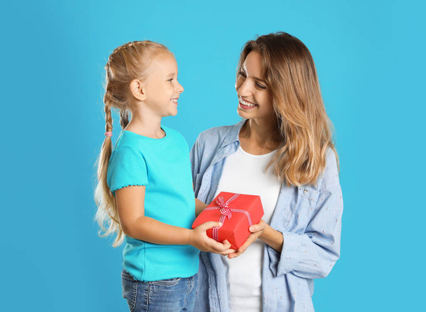 Little daughter congratulating her mom on blue background. Happy Mother's Day - Фото, изображение