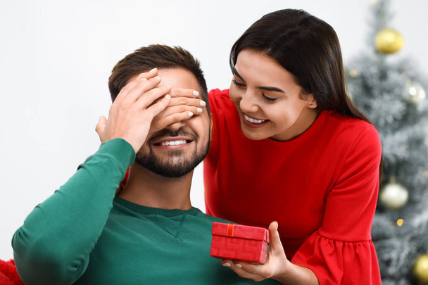 Young woman giving Christmas gift to her boyfriend at home - Foto, Bild
