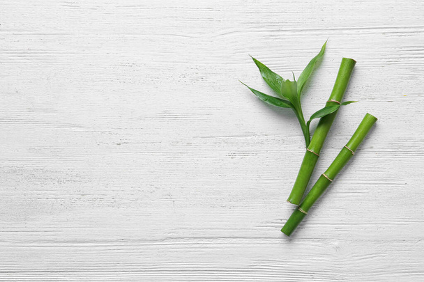 Hastes de bambu verde sobre fundo de madeira branca, vista superior. Espaço para texto
 - Foto, Imagem