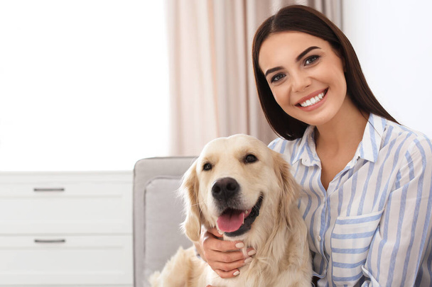 Young woman and her Golden Retriever dog in living room. Space for text - Foto, Bild