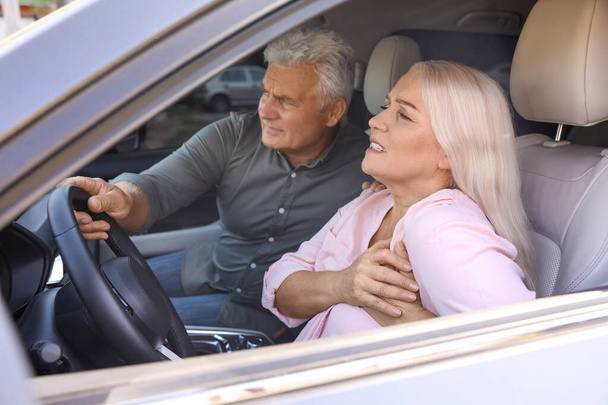 Senior man holding steering wheel while his wife having heart attack in car - Fotografie, Obrázek