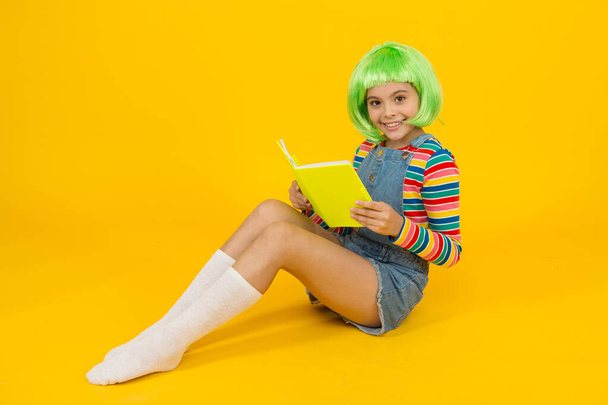 Détends-toi et lis le livre. Adorable petit enfant lire livre fond jaune. Petite fille mignonne aiment lire. Vous ne pouvez pas acheter le bonheur, mais vous pouvez acheter le livre. Une librairie. Bibliothèque. Bibliopole - Photo, image