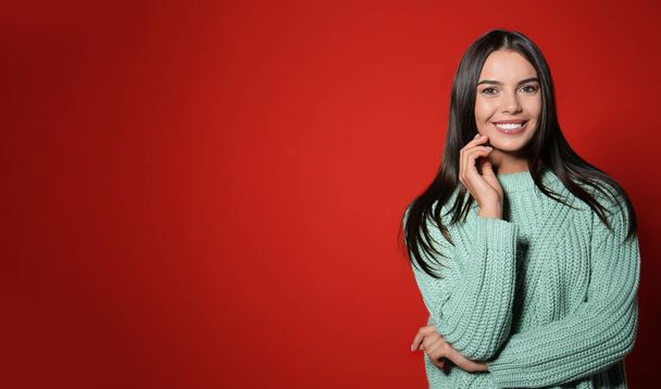 Young woman in warm sweater on red background. Space for text - Fotoğraf, Görsel