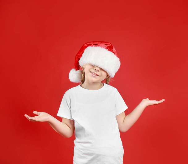 Cute little child wearing Santa hat on red background. Christmas holiday - Photo, image