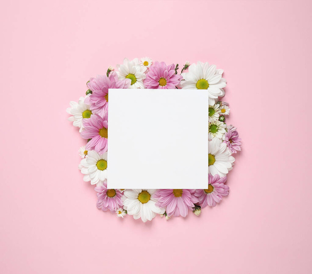 Beautiful chamomile flowers and paper card on pink background, flat lay with space for text - Photo, Image