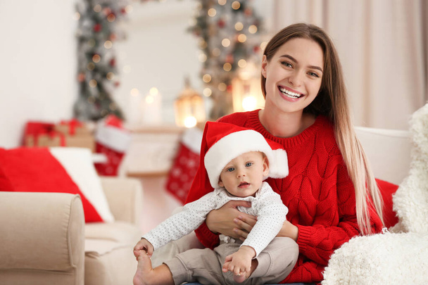 Happy mother with cute baby in room decorated for Christmas holiday - Фото, изображение