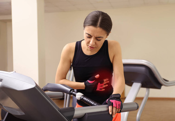 Junge Frau erleidet Herzinfarkt auf Laufband im Fitnessstudio - Foto, Bild