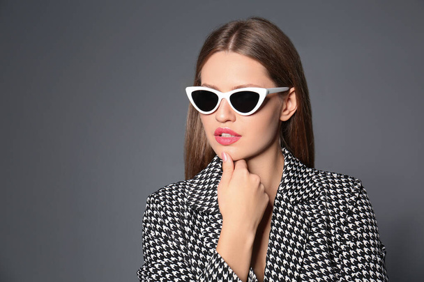 Young woman wearing stylish sunglasses on grey background. Space for text - Fotó, kép