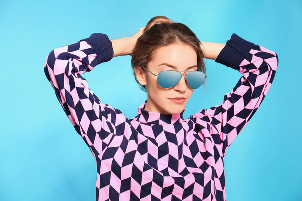 Young woman wearing stylish sunglasses on blue background - Foto, Imagem