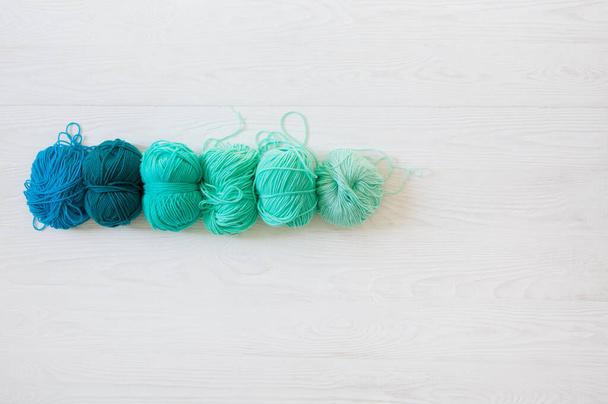 Yarn of green, turquoise, aquamarine and blue colors. White wood - Fotó, kép