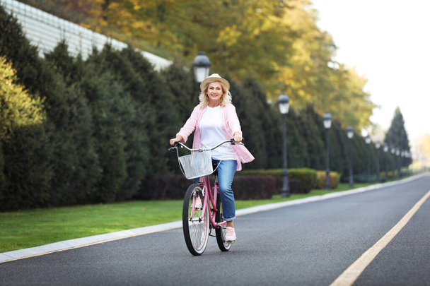 Mature woman riding bicycle outdoors. Active lifestyle - Photo, Image