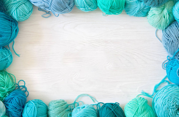 Yarn of green, turquoise, aquamarine and blue colors. White wood - Фото, зображення