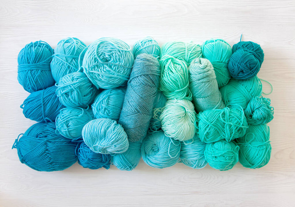 Yarn of green, turquoise, aquamarine and blue colors. White wood - Photo, image