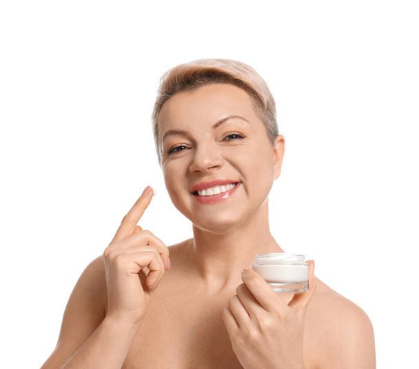 Rijpere vrouw met pot gezichtscrème op witte achtergrond - Foto, afbeelding