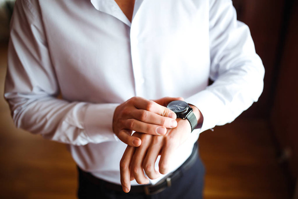 スタイリッシュな男性の腕時計は、男は時間を見ている。ビジネスマンの時計だ新郎は結婚式の前の朝に準備をします。ビジネスマンは腕時計の時刻を調べている。男性ファッション. - 写真・画像