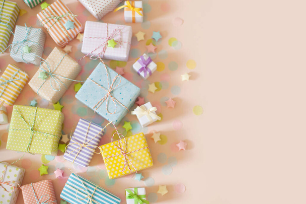 A lot of gifts and pastel color confetti. Pink background. - Фото, изображение