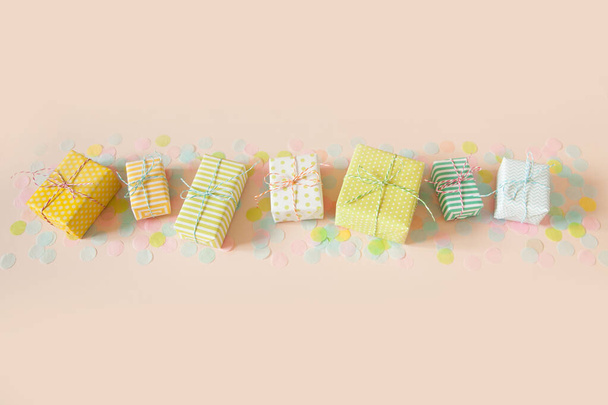 A lot of gifts and pastel color confetti. Pink background. - Фото, изображение