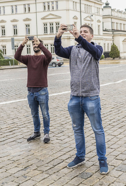 Deux jeunes touristes prenant des photos avec leurs mobiles à Sofia. Bulgarie
 - Photo, image