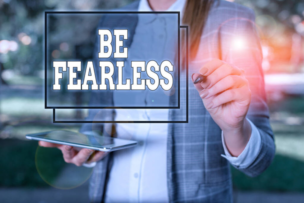 Handwriting text Be Fearless. Concept meaning act of living in spite of those things that scare you to death Outdoor background with business woman holding lap top and pen. - Photo, Image