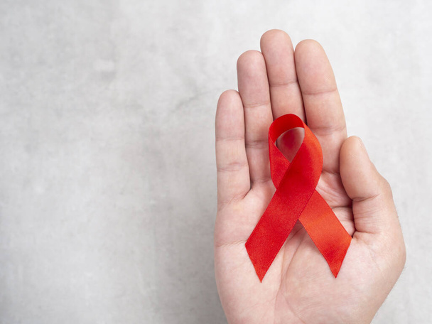 01 12月ヨーロッパの男性の手は、 HIVエイズの赤いリボンのシンボルを持ちます。コピースペース付きのトップビュー - 写真・画像